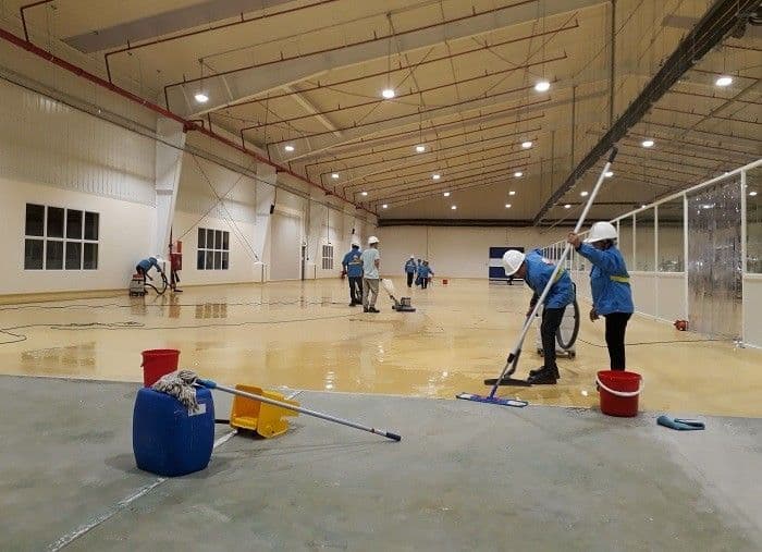 Industrial cleaning crew mopping and buffing a large polished commercial warehouse floor